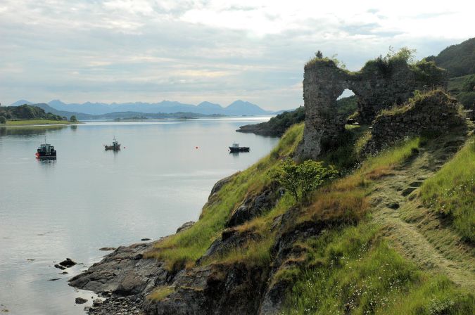 This view shows the Strome Castle ruins standing on their rocky promontory with the Cuillins on Skye in the background.